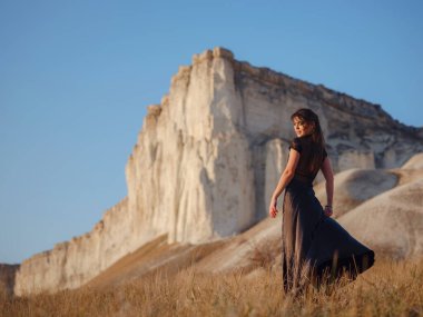 Dağın yakınındaki çöl tarlasında siyah elbiseli şık bir kadın. Vahşi batı. Yaz tatili dansı.