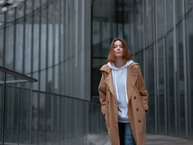 Güz bulutlu Moskova Zaryadye Parkı 'nda, güzel bej ceketli güzel bir kadın yürüyor. Sokak tarzı. Rusya 'ya Seyahat.
