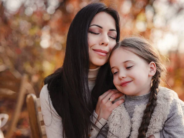 Fashionable mother with daughter. Family in a autumn park. spending weekend, picnic in autumn forest together. Mother and child relations.