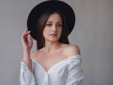 Beauty, fashion studio portrait of young woman with pearl makeup in black hat isolated on white background. Aesthetics of minimalism. Concept for spa, wedding salons, beauty treatments.