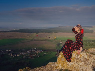 Boho 'lu kadın White Rock' ta güneşin doğuşunu seyrediyor. Kırmızı elbiseli güzel bir kadın. Kırsal kesimdeki çiftlikte yaşam tarzı açık hava portresi. Vahşi batı. Yaz tatili.