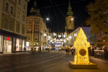 Graz, Avusturya-19 Kasım 2021: Avusturya 'nın Steiermark kentindeki Herrengasse caddesindeki ünlü Saat Kulesi ile güzel Noel süslemeleri. Harekete uzun süre maruz kalma