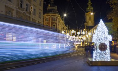  Avusturya 'nın Steiermark kentindeki Graz şehrinde, Herrengasse caddesinde ünlü Saat Kulesi' ne sahip güzel Noel süslemeleri. Harekete uzun süre maruz kalma