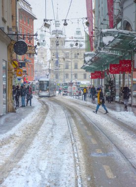 Graz, Avusturya-09 Aralık 2021: Arkaplanda, Avusturya 'nın Steiermark kentinde kış günü yoğun kar ve belediye binasında yürüyen insanlar