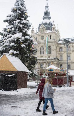 Graz, Avusturya-09 Aralık 2021: Avusturya 'nın Steiermark kentindeki belediye binası ile Hauptplatz Meydanı' nda kış günü yoğun kar altında yürüyen insanlar