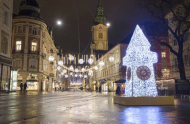 Graz, Avusturya-02 Aralık 2021: Avusturya 'nın Steiermark kentindeki Herrengasse caddesindeki ünlü Saat Kulesi ile güzel Noel süslemeleri. Seçici odak