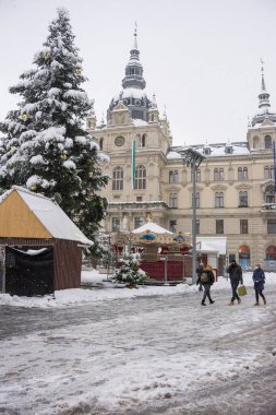 Graz, Avusturya-09 Aralık 2021: İnsanlar kış günü Avusturya 'nın Steiermark kentindeki belediye binası ile birlikte Hauptplatz Meydanı' nda kar üzerinde yürüyorlar.