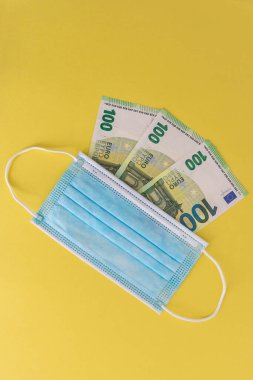 Tıbbi maskeler ve Avrupa para birimi banknotları. Coronavirüs kayıpları nedeniyle mali kriz, seçici odaklanma