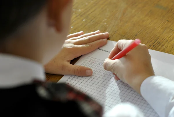 Schoolboy writes in a notebook — Stock Photo, Image