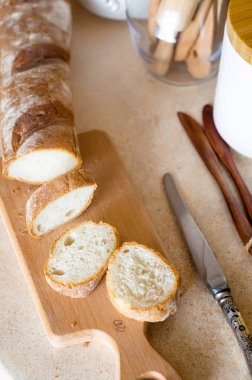 Dilimlenmiş Fransız Ekmeği. Kahvaltı için malzemeler, taze baget ve arka plandaki mutfak aletlerinde domates, İskandinav tarzı. Seçici odak