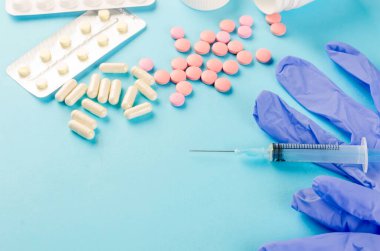 İlaç konsepti, çeşitli haplar, şırınga, mavi arka planda tıbbi eldivenler, fotokopi alanı modeli, düz yatak.