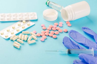 İlaç konsepti, çeşitli haplar, şırınga, mavi arka planda tıbbi eldivenler, fotokopi alanı modeli, düz yatak.