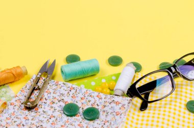 Dikiş için bir takım aksesuarlar, iplik makaraları, kumaşlar, makas, yüksük ve gözlük. Terzilik konsepti, yama ve el işi. Dikiş ve dikiş..
