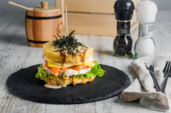 Sushi burger made from rice bread with salmon,  lettuce and wasabi sauce. Sushi-food hybrids trend. asian style gluten free.