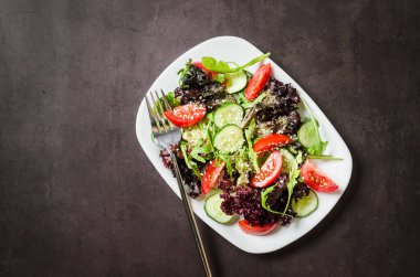 Healthy vegetable salad with fresh salad leaves, arugula, cherry tomato, cucomber and parsley in plate. Summer food concept. Selective focus
