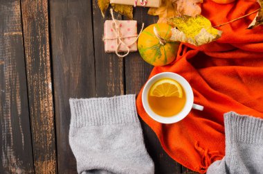 Sonbahar hala hayattır. Limonlu sıcak çay, ahşap arka planda sarı akçaağaç yaprakları ve rahat süveter. Sonbahar havası, sonbahar dekoru, sonbahar mevsimi konsepti. Şükran Günü ve Cadılar Bayramı tatili. düz yat, 