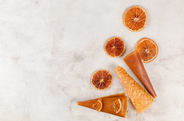 Assorted pastille rolls. Fruit leather pastille cones and dried oranges on light grey bacground. Healthy eating concept, snack, no sugar.