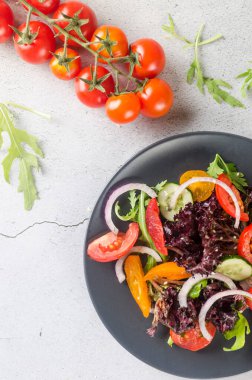 Healthy vegetable salad with fresh salad leaves, arugula, cherry tomato, cucomber and parsley in plate. Summer food concept. Selective focus