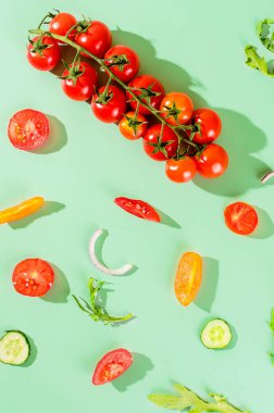Fresh tomatoes and cucumbers on a green background with hard shadows. Healthy  salad ingredients. Minimal seasonal creative concept.