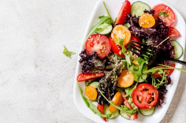 Healthy vegetable salad with fresh salad leaves, arugula, cherry tomato, cucomber and parsley in plate. Summer food concept. Selective focus