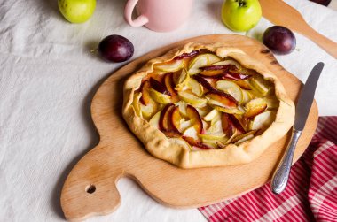 Beyaz keten masa örtüsü üzerinde elma ve erikli ev yapımı galet. Açık turta. Masadaki ev yapımı turta kabuğunun en üst görüntüsü. Kırsal ev yapımı meyveli turta..
