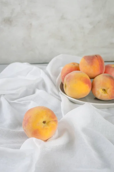 Fresh ripe  peaches on a white plate. Harvest of peaches for food. Still life in minimalistic rustic style.
