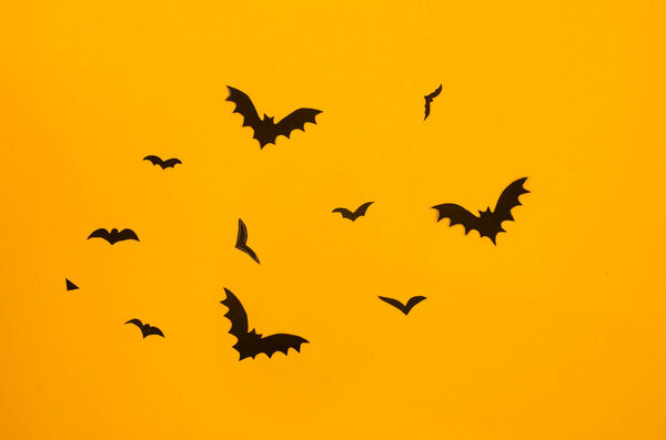 желтый фон с черными бумажными летучими мышами. Концепция украшения Хэллоуина