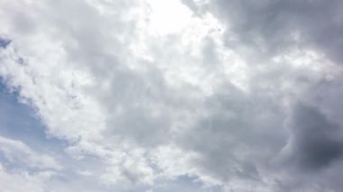 Büyük beyaz ve gri bulutlar mavi arka planda hareket ediyor ve yuvarlanıyor. 4k hızlandırılmış görüntü.