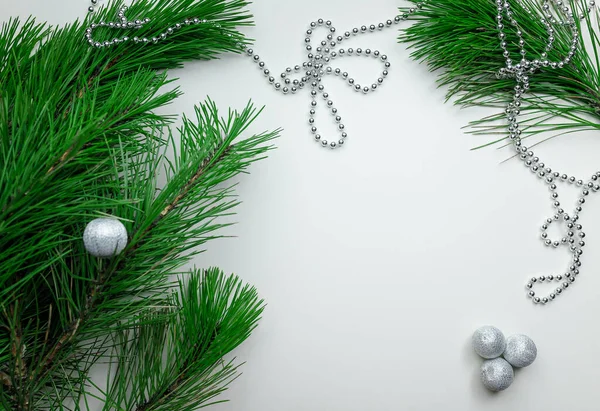 Noel tatili geçmişi - beyaz masa arka planında süsleme. Yeni yıl çamı ve gümüş Noel baloları. Üst Manzara. Metin için yer.