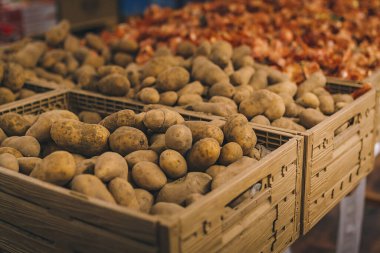 Alışveriş merkezinde, süpermarkette, alışveriş merkezinde bir kutu taze patates. Arkaplana odaklanmamış soğanlar.