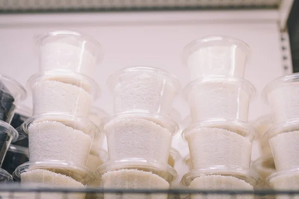 Raflardaki küçük plastik kaplarda hindistan cevizi taneleri. Market, gıda mağazası, süpermarket. Pastane malzemeleri, tatlılar..