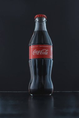 İzmail, Ukrayna. Nisan 2022. Siyah arka planda Coca Cola şişesi. Klasik popüler içecek, tatlı soda, ünlü ürün.