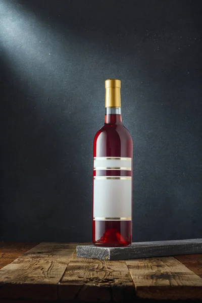 Bottle of red dry varietal wine Red Rose from Ukrainian grape sort Odesa black on wooden background. Alcohol drink template mockup