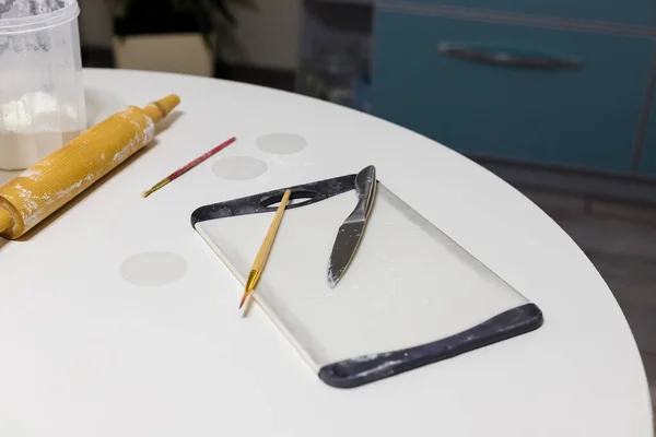 Kitchen board, brushes and dough rolling pin in some flour on white round table. Homemade pastry, bakery, cooking food concept