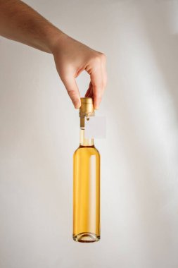 Elinde küçük bir şişe kuru beyaz şarap ya da markasız tatlı likör var. Sahte şablon. Dikey çekim, beyaz arkaplan