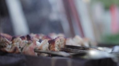 Salamuraya yatırılmış domuz eti parçalarının şiş çevrildiği ve şenlik ateşinde kızartıldığı yumuşak odaklı bir çekim. Kebap ya da çok dumanlı geleneksel shashlik yemeği..