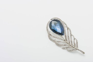 Tüylü metalik altın broş, parlak mavi değerli taş taklidi, beyaz arka planda iğne, bijouterie, yakın takı