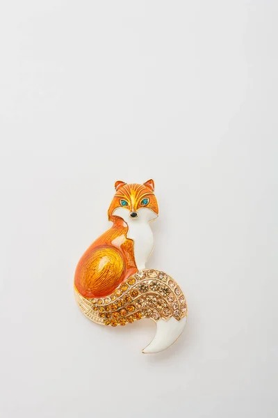 Metallic brooch in shape of fox with orange gemstone imitation, pin isolated on white background, bijouterie, jewelry close up