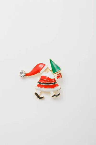 Metallic cute brooch in shape of Santa Claus holding Merry Christmas tree, pin on white background, bijouterie, jewelry close up