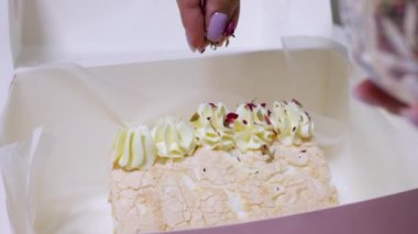 Şekerci kadın elleri pembe bir kutuda gül yapraklarıyla pasta süslüyor. Sevgililer günü için ev yapımı tatlı, anneler günü.