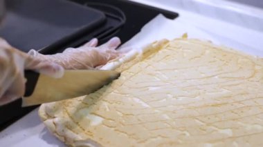 Eldiven giymiş kadın eller, bıçakla kesilmiş taze pişmiş meringue çarşafı. Ev yapımı tatlı tatlı. Hamur işi pişirme işlemi