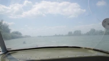 Nehrin güzel manzarası, yeşil doğa, mavi gökyüzü, motorlu sandaldan kırık ön cama doğru. Sürat teknesi suda yüzüyor, yaz tatili, turizm