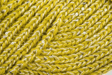 Ürün, tellerdeki çeşitli döngülerle birbirine bağlı yünlü ipliklerden yapılmıştır.