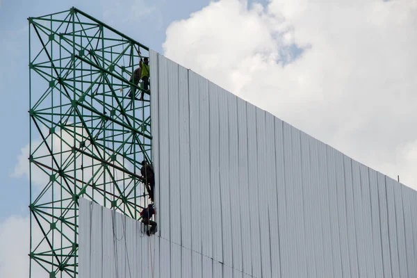 Pracownicy Instalujący Blachy Dużym Billboardzie Tłem Niebieskiego Nieba Białej Chmury — Zdjęcie stockowe