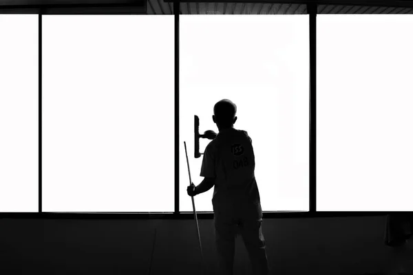 man worker cleaning window glass in black and white