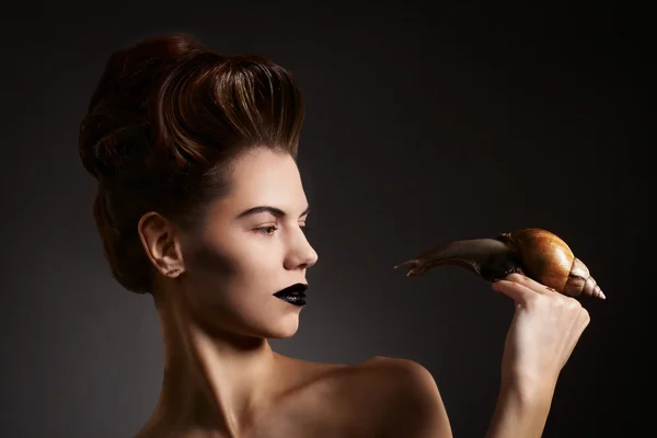 Beautiful woman with snail with black eyes and lips. Fashion. Go — Stock Photo, Image