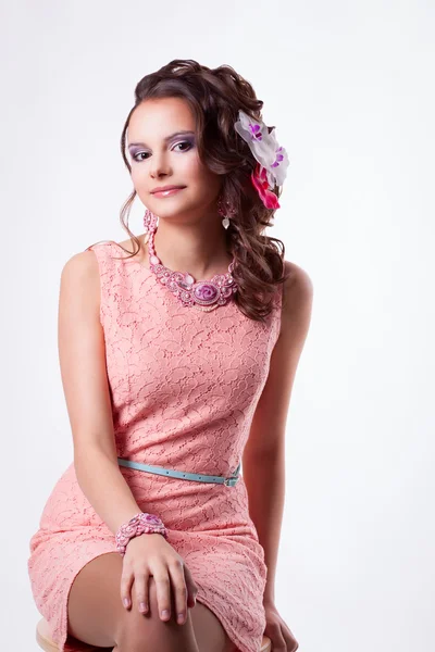 Niedliches Mädchen mit Blumen im Haar in einem rosa Kleid lächelt — Stockfoto