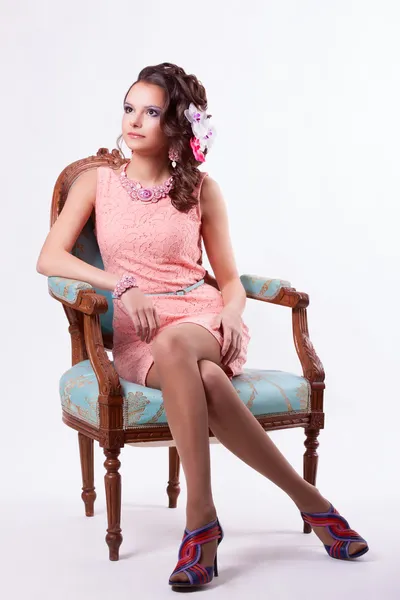 Brunette in a pink dress sitting on a chair in baroque style — Stock Photo, Image