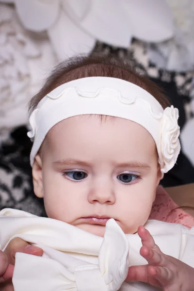 6 meses bebê menina em um vestido branco olha para o arco engraçado no dre — Fotografia de Stock