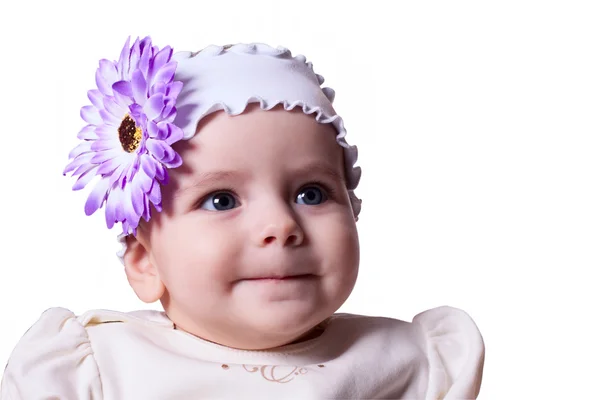Niña de 6 meses con una flor en la cabeza sonriendo en un blanco — Foto de Stock